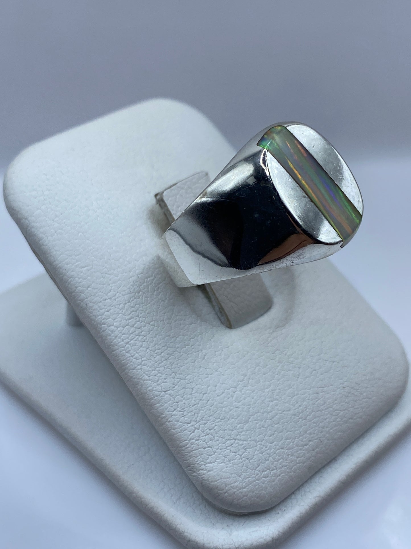 Detalle lateral del anillo mostrando el bisel pulido y el juego de colores del ópalo