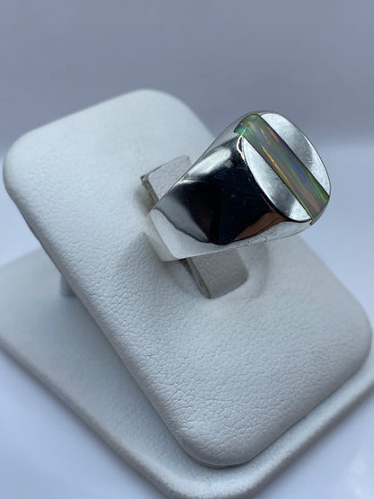 Detalle lateral del anillo mostrando el bisel pulido y el juego de colores del ópalo