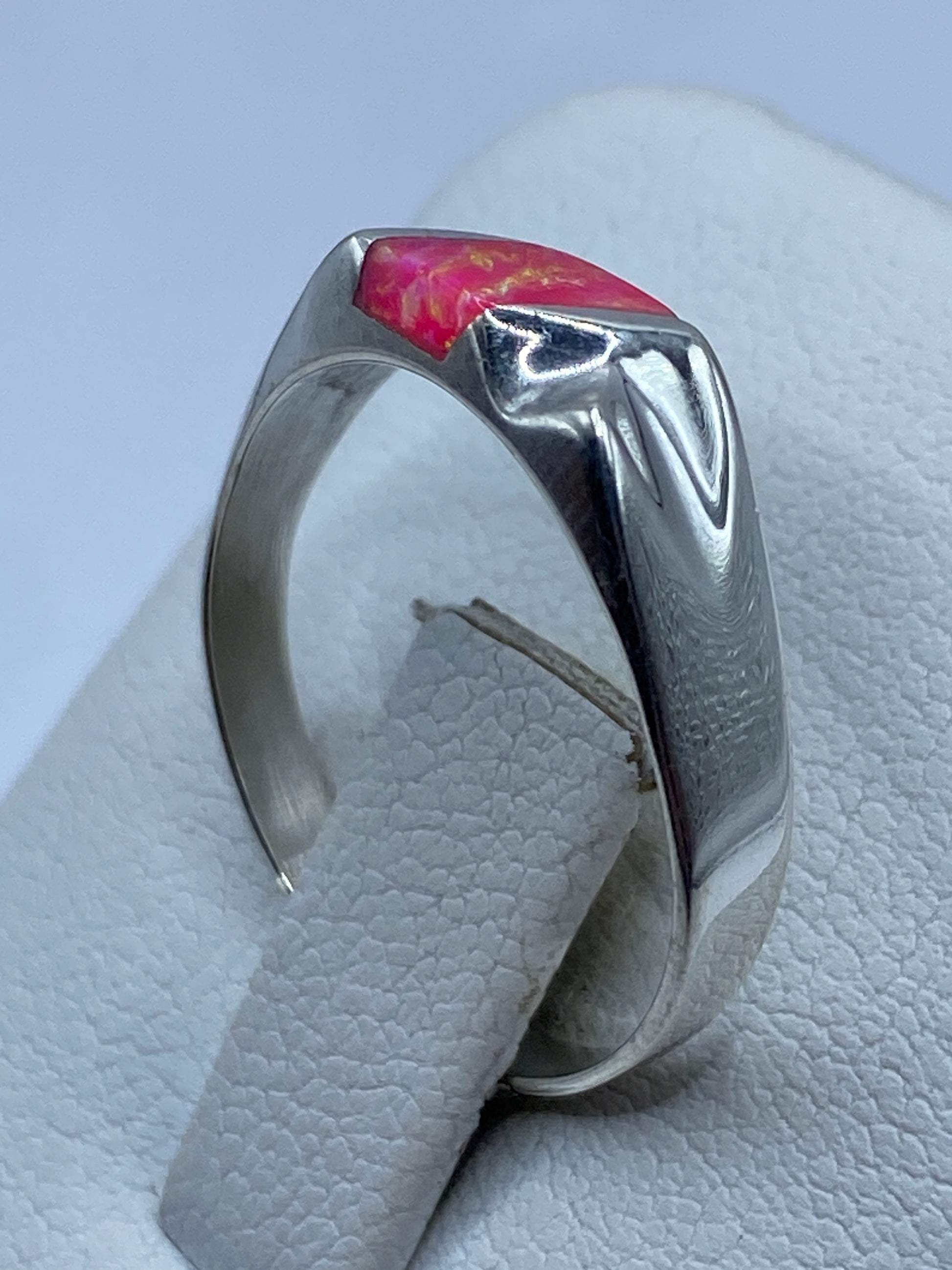 Anillo puesto en dedo de mujer mostrando el juego de colores del ópalo rosa
