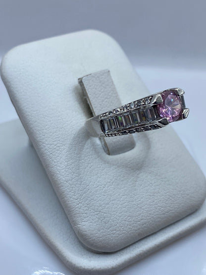 Vista frontal del anillo mostrando la circonia rosa facetada y los flancos de plata trabajada