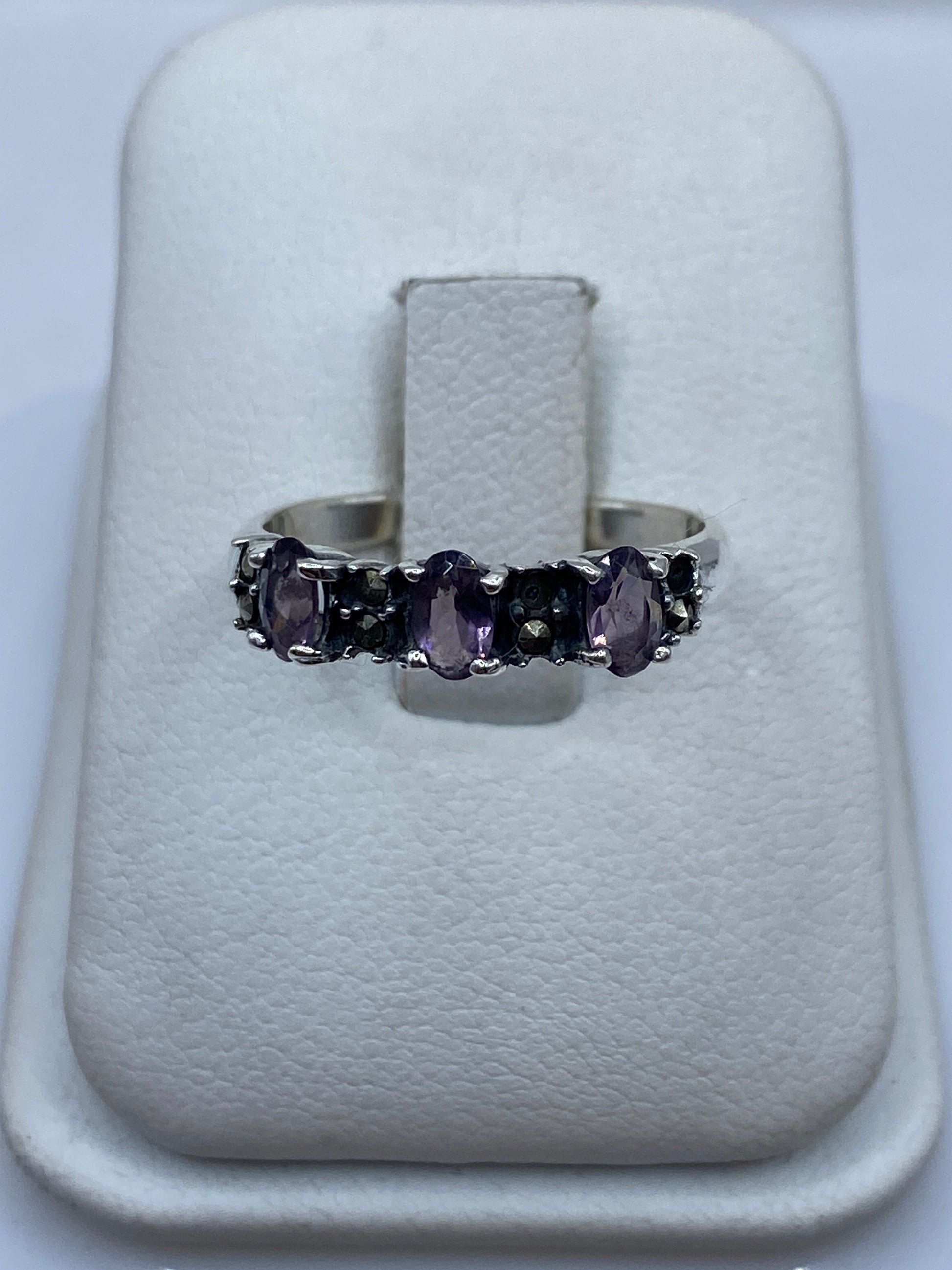 Anillo de plata con circonia morada facetada en la mano de una mujer