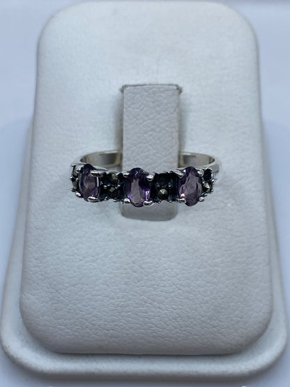 Anillo de plata con circonia morada facetada en la mano de una mujer