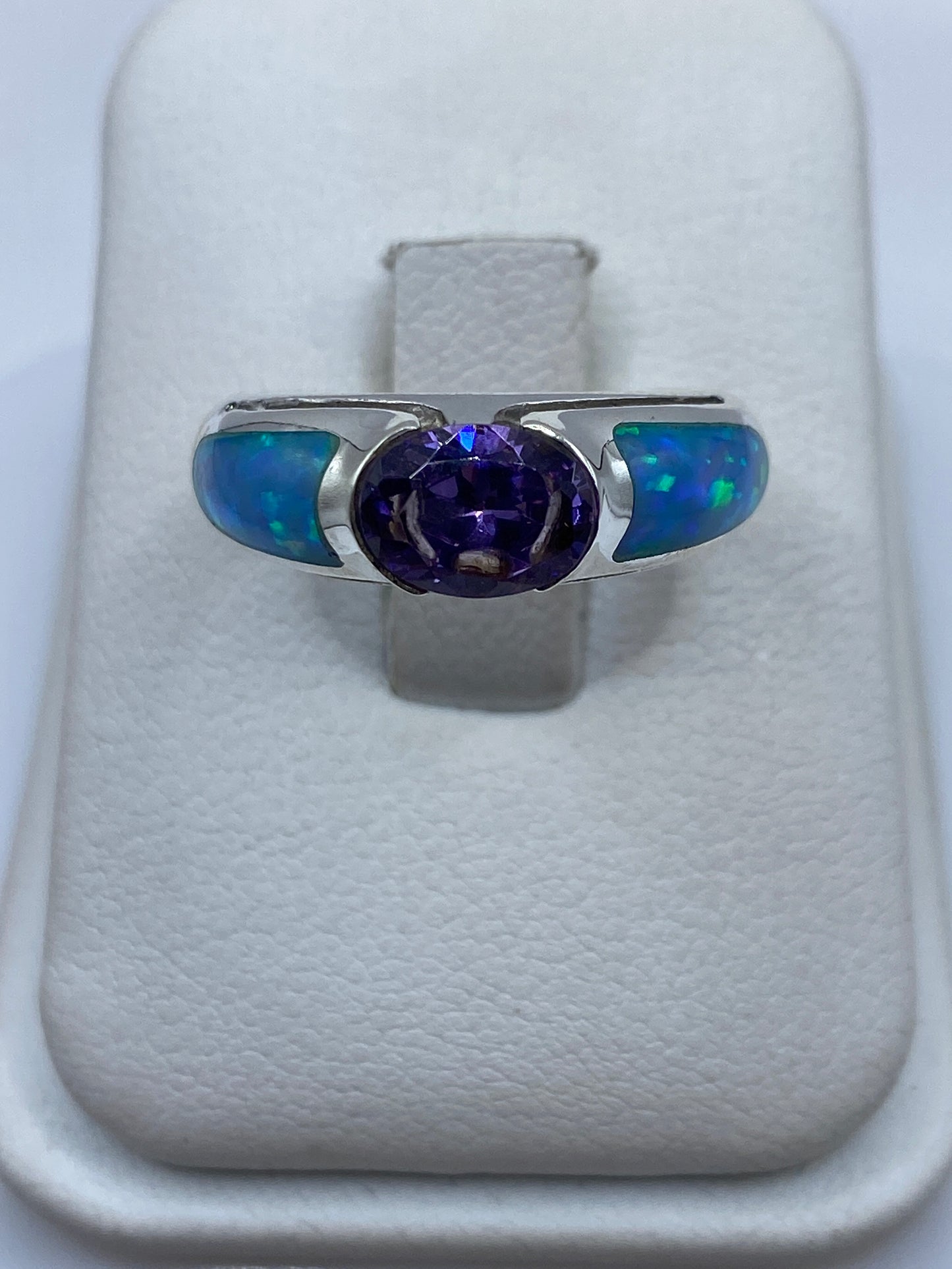 Anillo de plata .950 con ópalo de fuego azul, sostenido en mano femenina mostrando juego de colores