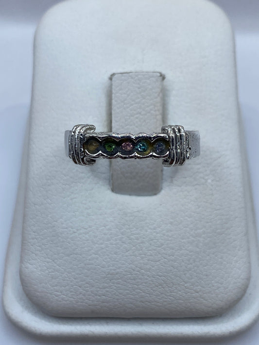 Anillo de plata con cinco circonias multicolor en frente, mostrando los tonos azul, verde, ámbar y transparente