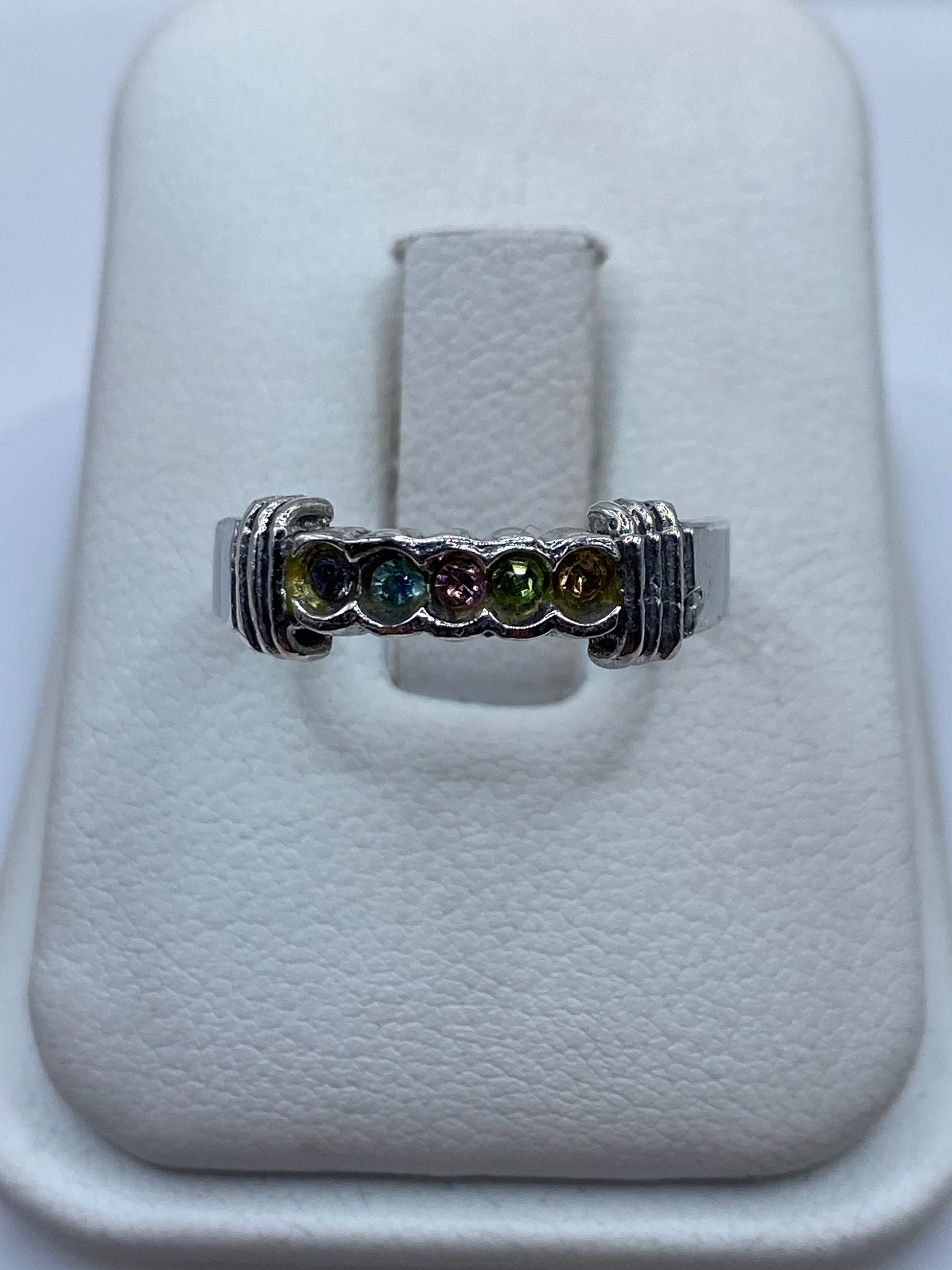 Anillo de plata con circonia multicolor en tonos ámbar, verde y azul sobre el dedo
