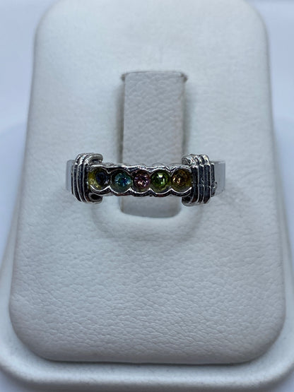 Anillo de plata con circonia multicolor en tonos ámbar, verde y azul sobre el dedo