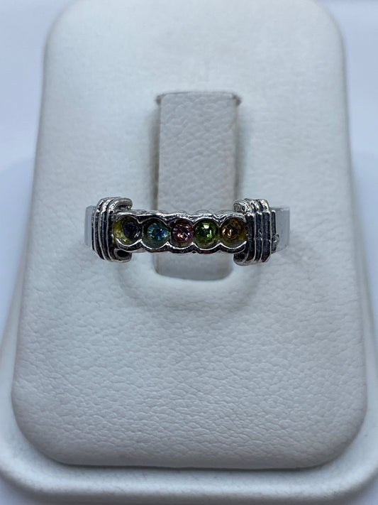 Anillo de plata con circonia multicolor en tonos ámbar, verde y azul sobre el dedo