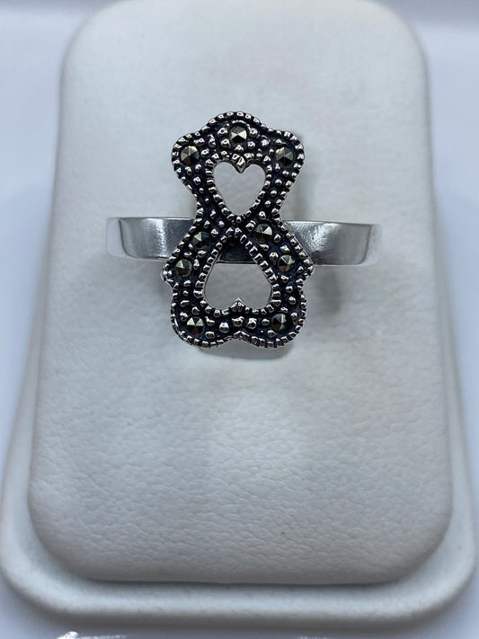 Anillo de plata doble corazón texturizado en mano de mujer, talla 10
