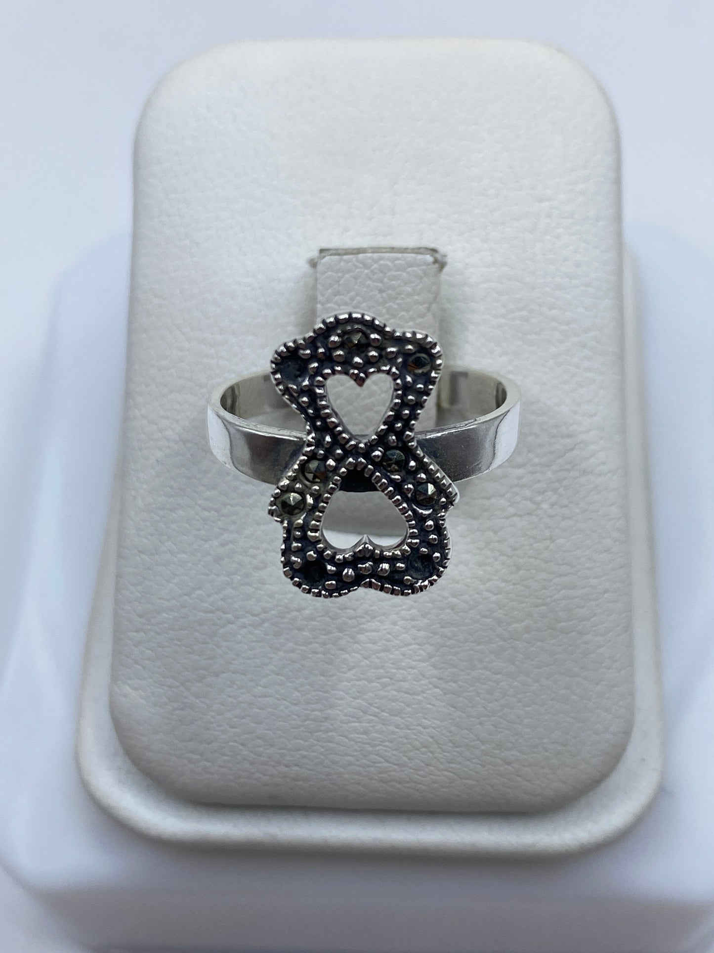 Anillo de plata lazo minimalista con piedra en la mano de una mujer
