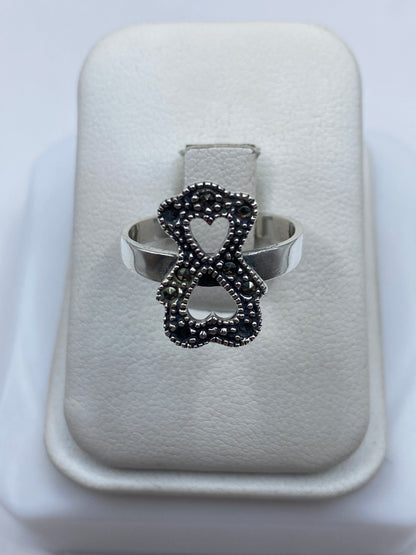 Anillo de plata lazo minimalista con piedra en la mano de una mujer