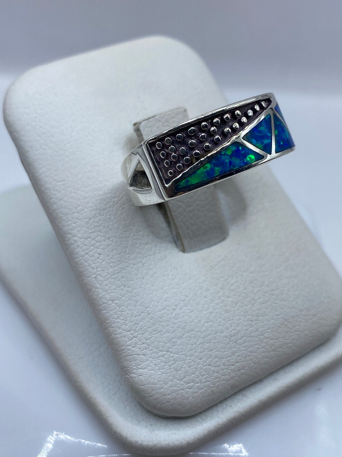Detalle lateral del anillo mostrando la textura artesanal y el juego de color azul-verde del ópalo