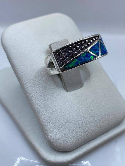 Detalle lateral del anillo mostrando la textura artesanal y el juego de color azul-verde del ópalo