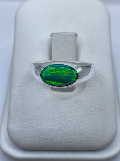 Anillo de plata .950 con ópalo de fuego verde en presentación formal sobre cojín blanco