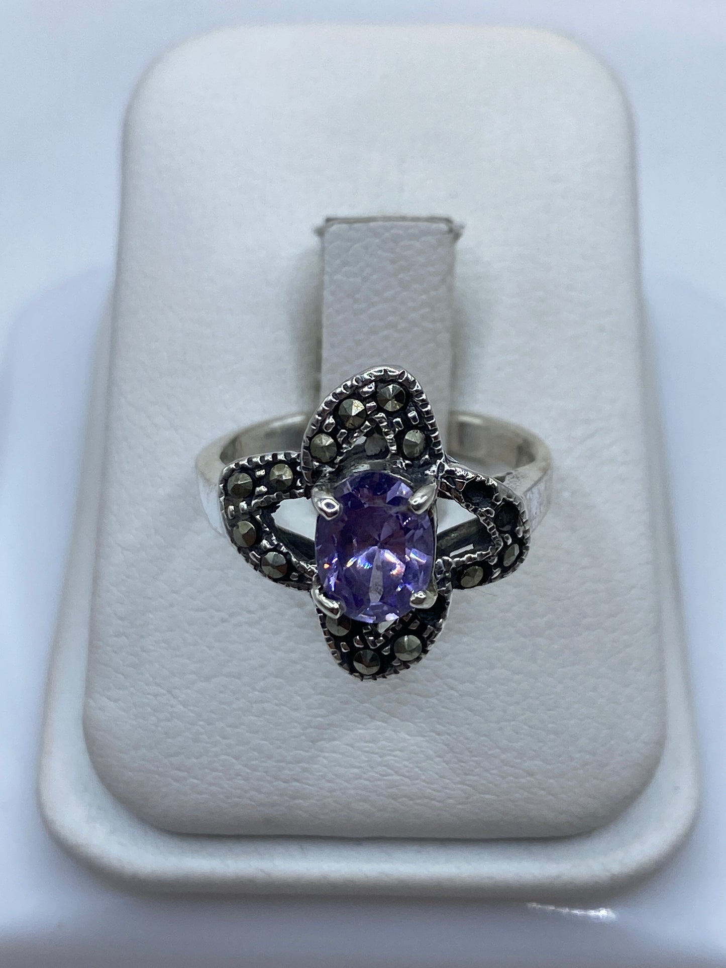 Anillo de plata solitario con circonia morada facetada en la mano de una mujer