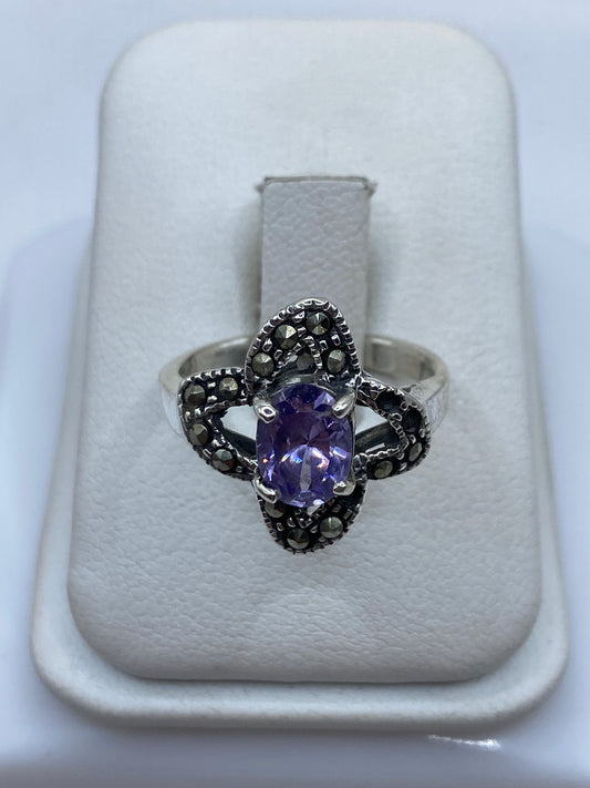 Anillo de plata solitario con circonia morada facetada en la mano de una mujer