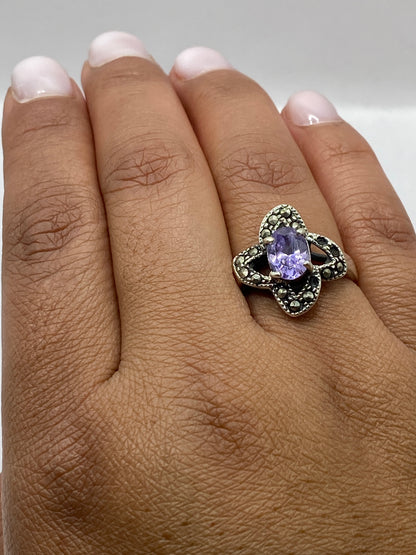Anillo solitario sobre fondo blanco destacando la circonia morada y el sello 925