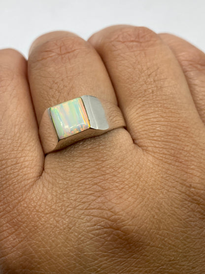 Ópalo de fuego multicolor en anillo de plata .950 sobre fondo gris mostrando variación de colores