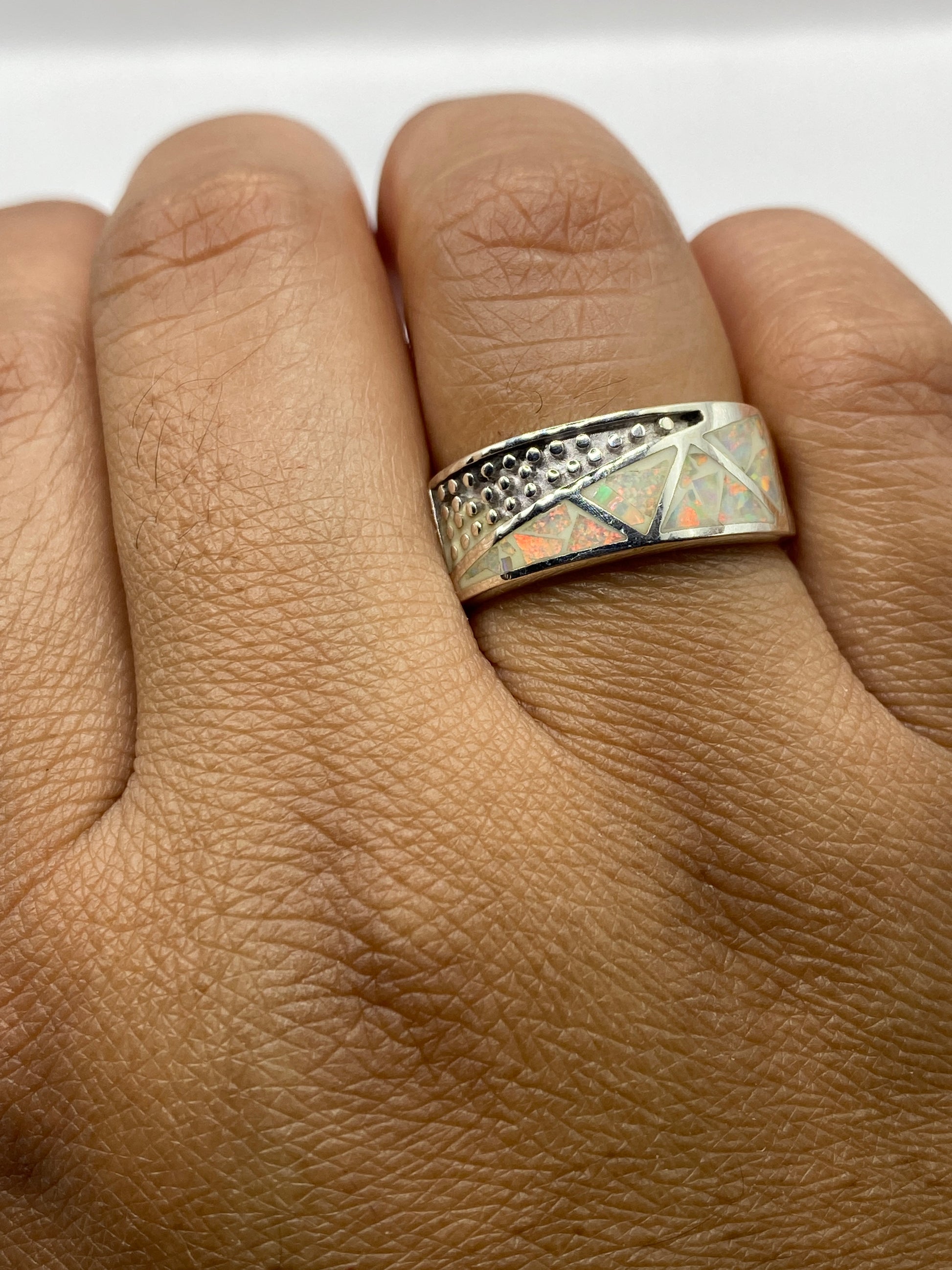 Anillo ópalo de fuego en la mano mostrando el juego de color desde ángulo lateral