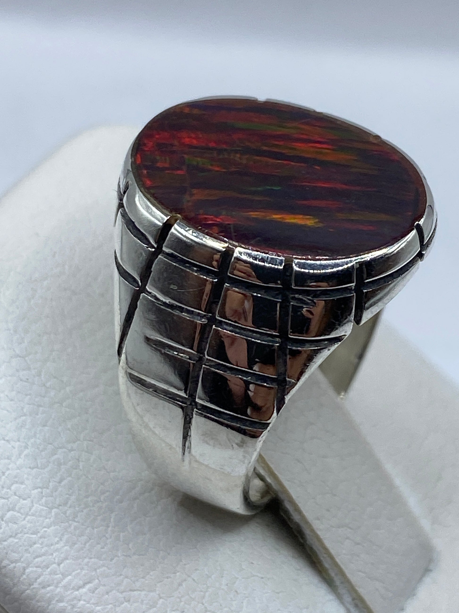 Anillo colocado en dedo mostrando el fuego rojo del ópalo natural con destellos verdes