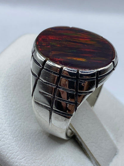 Anillo colocado en dedo mostrando el fuego rojo del ópalo natural con destellos verdes