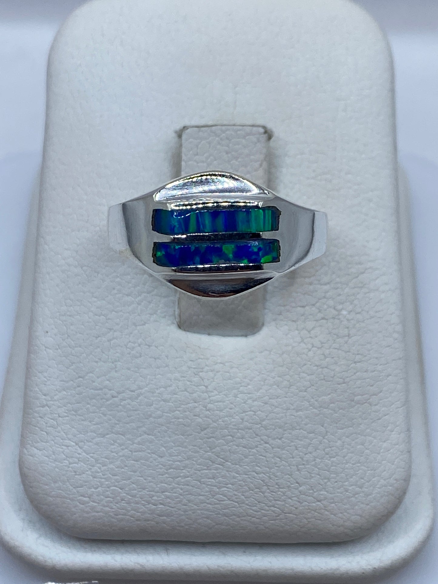 Anillo de plata con ópalo de fuego azul en la mano de una mujer