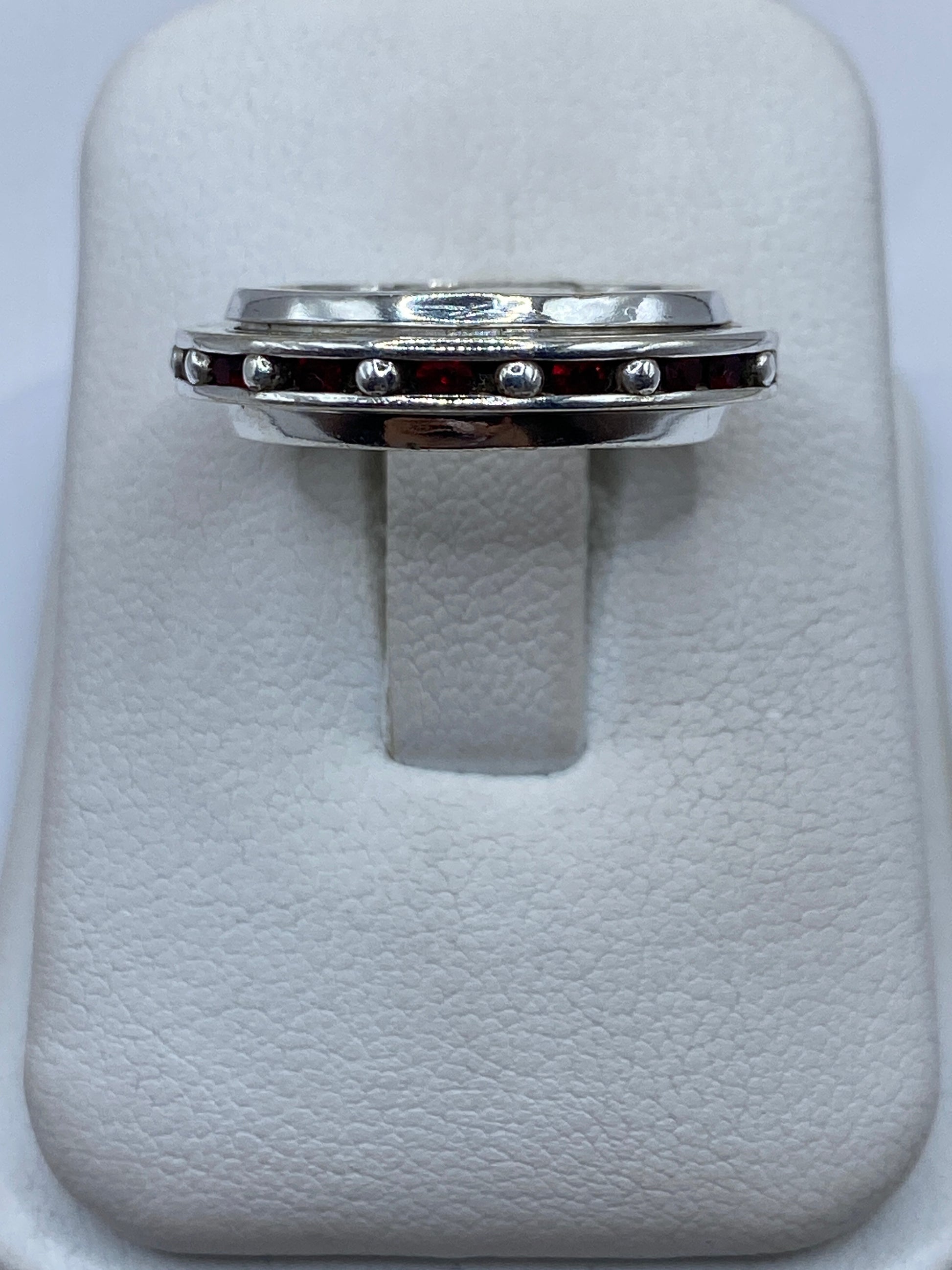 Anillo de plata con circonia roja tipo rubí en caja de presentación blanca, vista superior