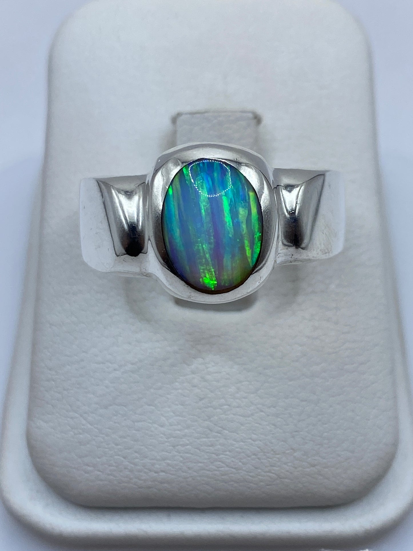 Anillo de plata solitario con ópalo de fuego azul y verde en joyero blanco