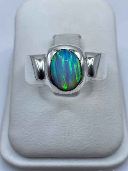 Anillo de plata solitario con ópalo de fuego azul y verde en joyero blanco