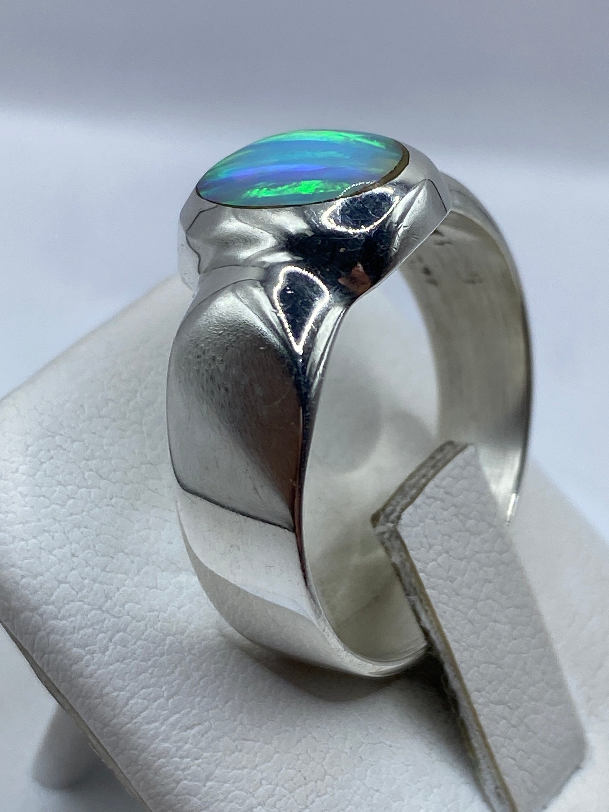 Anillo con ópalo de fuego en la mano mostrando el juego de color azul y verde
