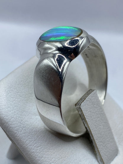 Anillo con ópalo de fuego en la mano mostrando el juego de color azul y verde