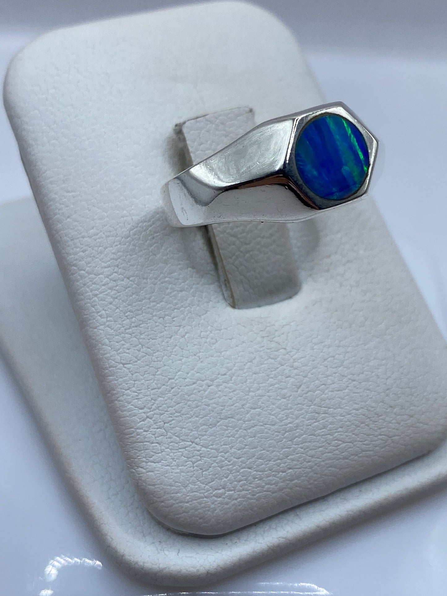 Vista frontal del anillo mostrando la piedra de ópalo con destellos verdes y azules