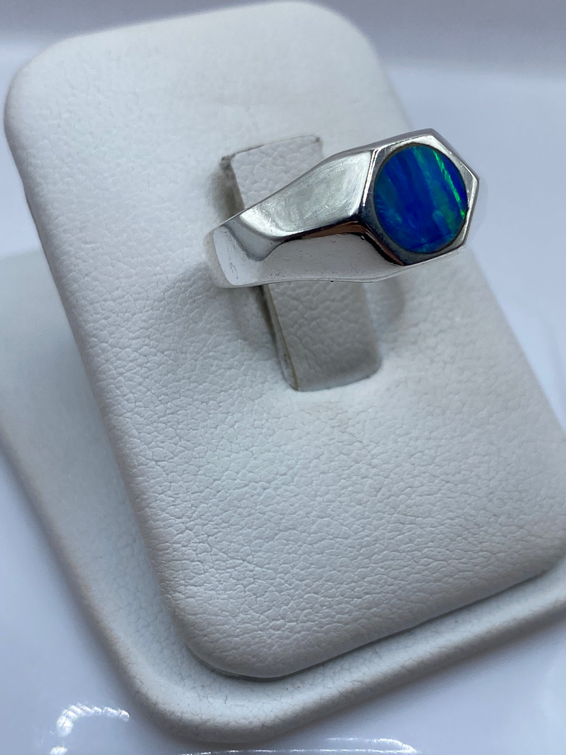 Vista frontal del anillo mostrando la piedra de ópalo con destellos verdes y azules