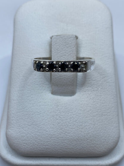 Anillo de plata circonia negra solitario en la mano de una mujer con manicura francesa