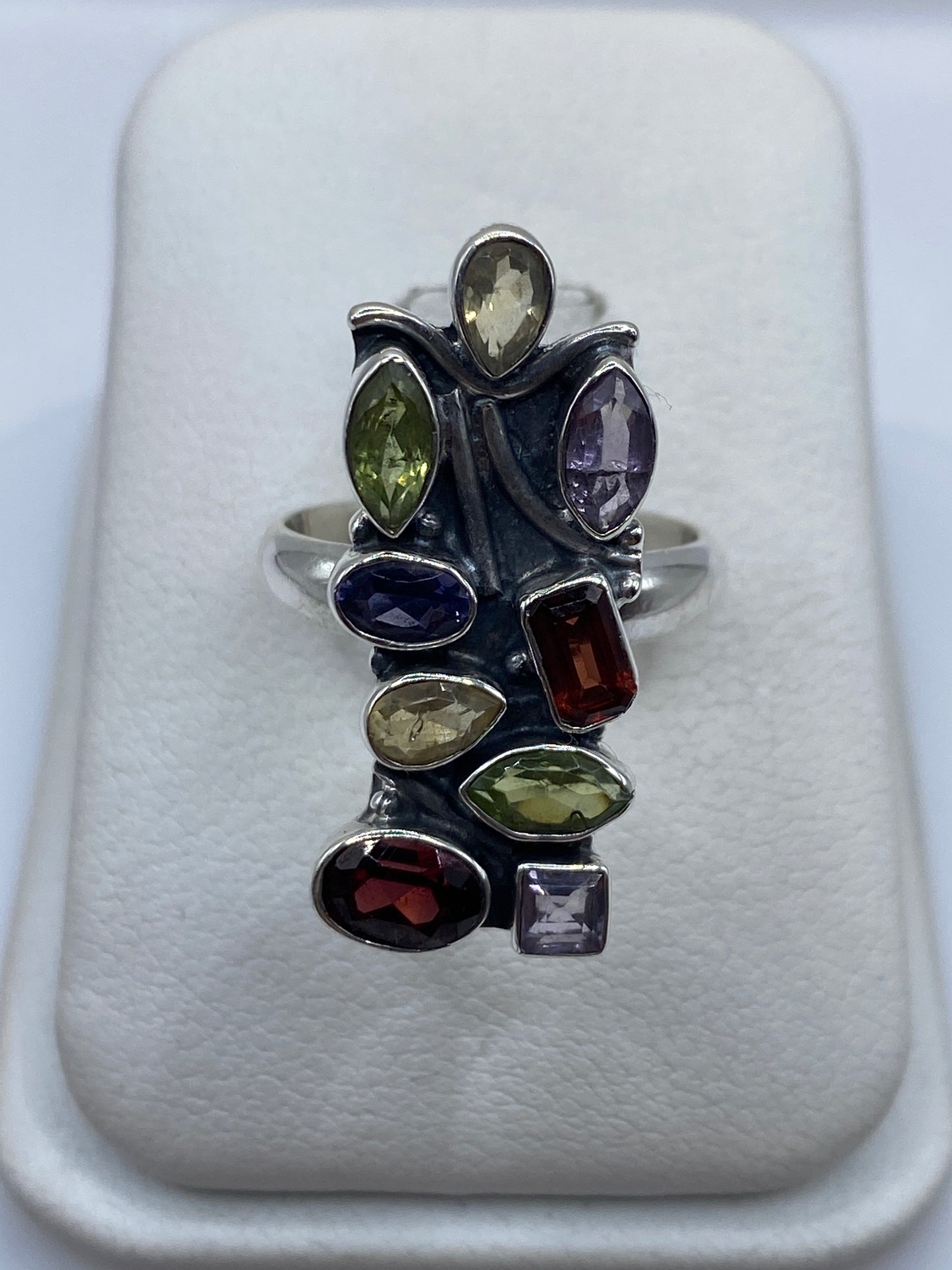 Anillo de plata con nueve circonias multicolor en diseño geométrico moderno, sobre dedo de mujer