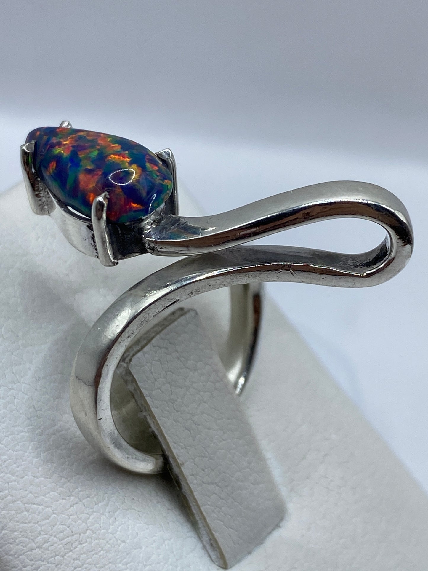 Anillo orgánico de plata sobre dedo, luciendo el fuego del ópalo