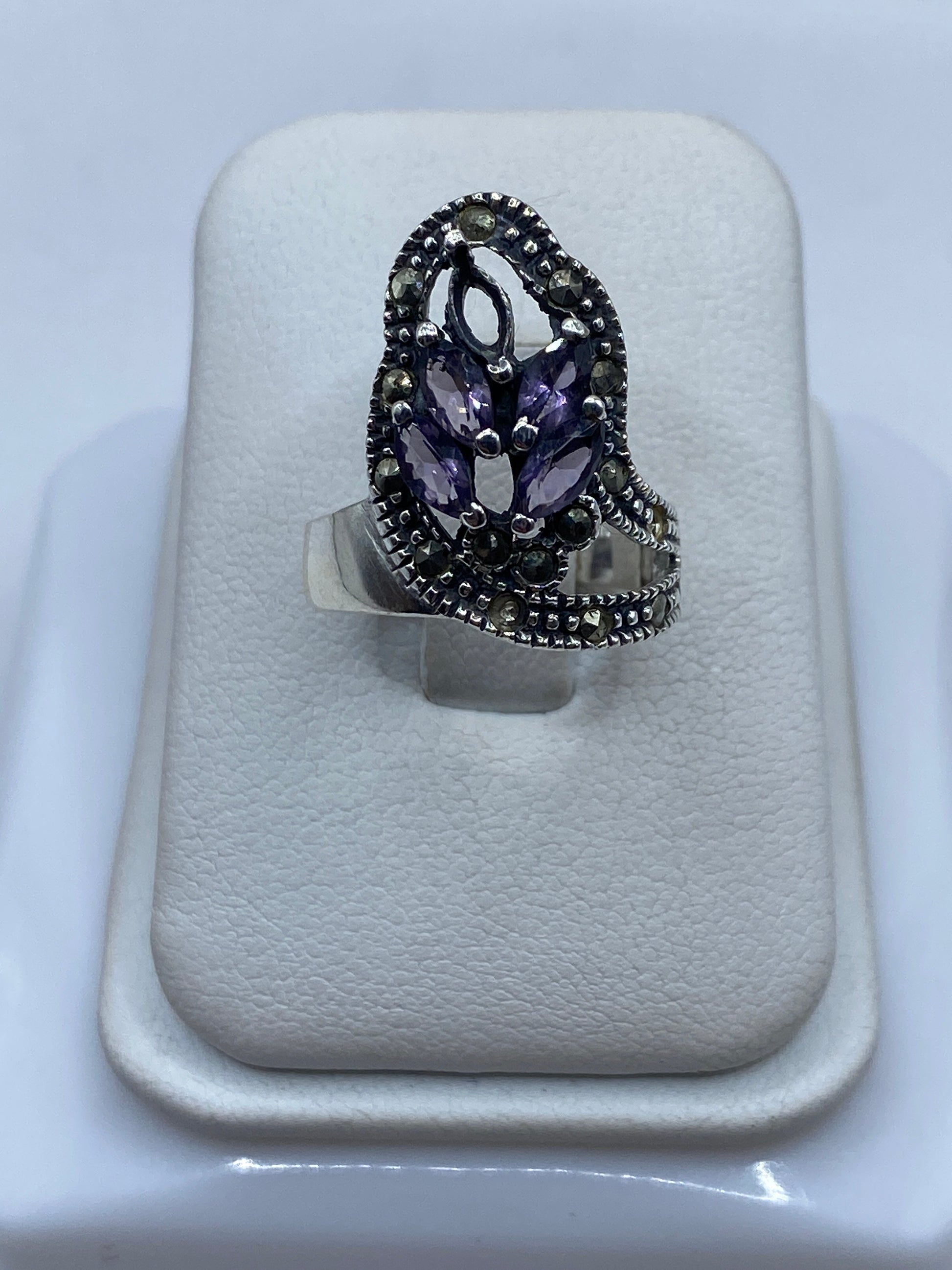 Anillo solitario de plata con circonia morada ovalada en la mano de una mujer