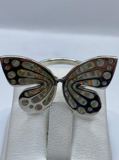 Anillo de alas sobre dedo, ópalo de fuego brillando con fuego naranja y verde