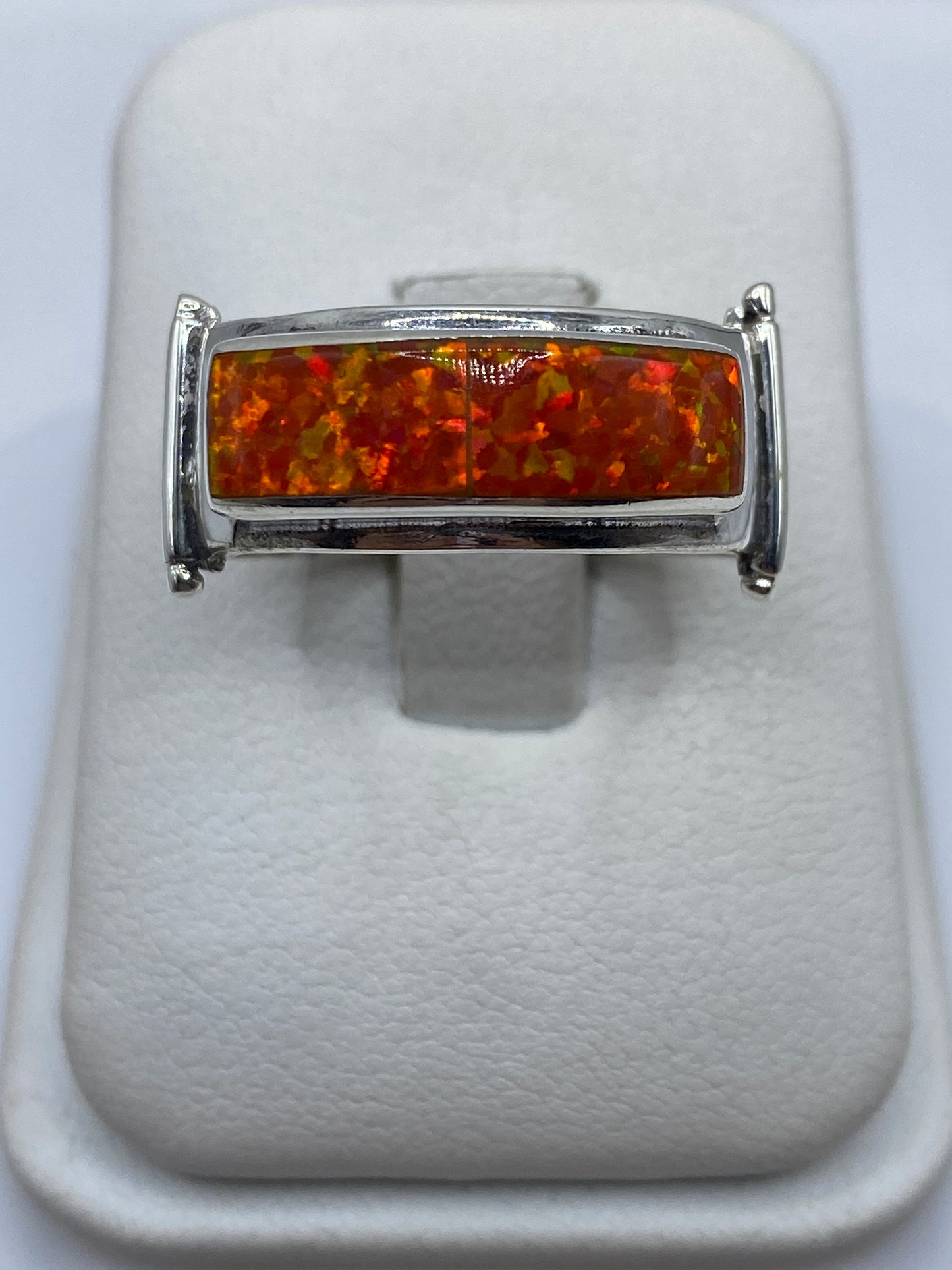 Anillo de plata .950 con ópalo de fuego naranja en la mano de un hombre