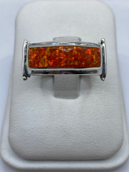Anillo de plata .950 con ópalo de fuego naranja en la mano de un hombre
