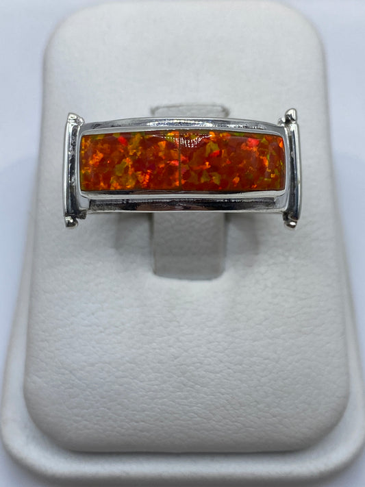 Anillo de plata .950 con ópalo de fuego naranja en la mano de un hombre