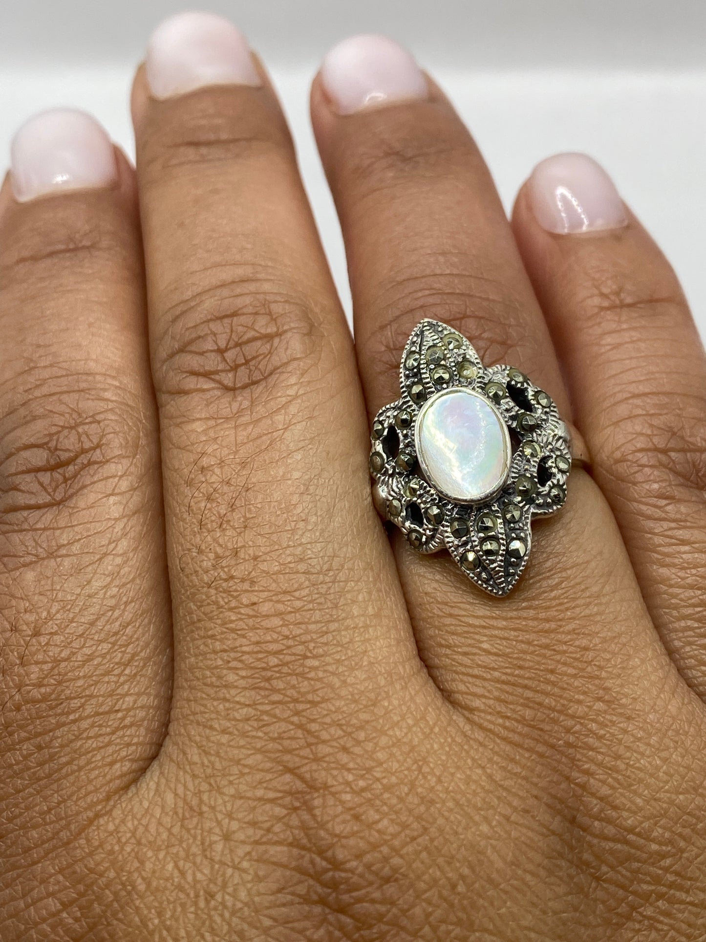Anillo vintage de plata sobre fondo gris mostrando sello .925 y marco ornamentado