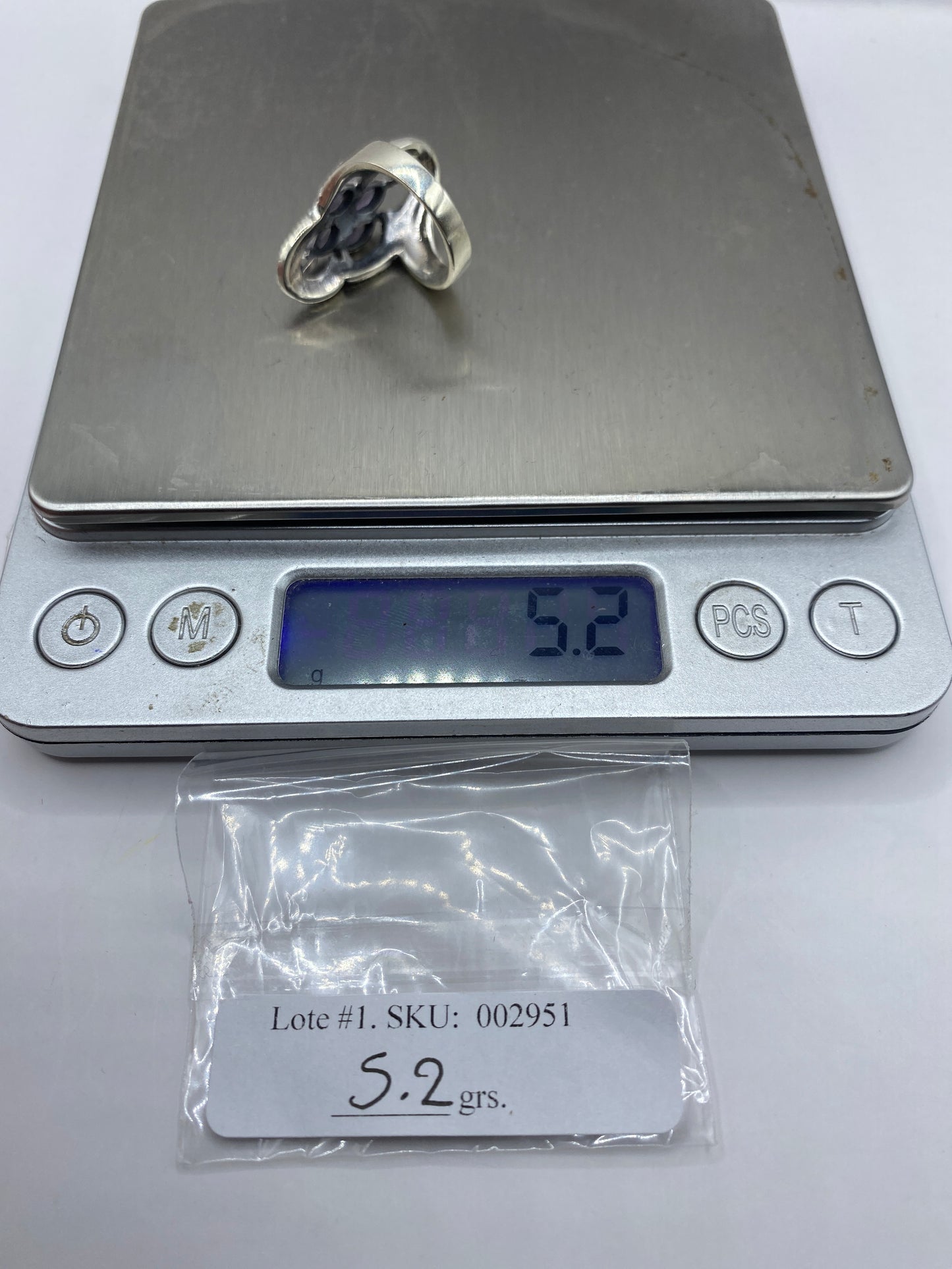 Anillo solitario de plata con circonia en la mano de una mujer sobre fondo gris