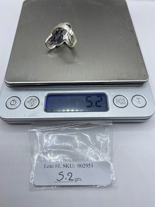Anillo solitario de plata con circonia en la mano de una mujer sobre fondo gris