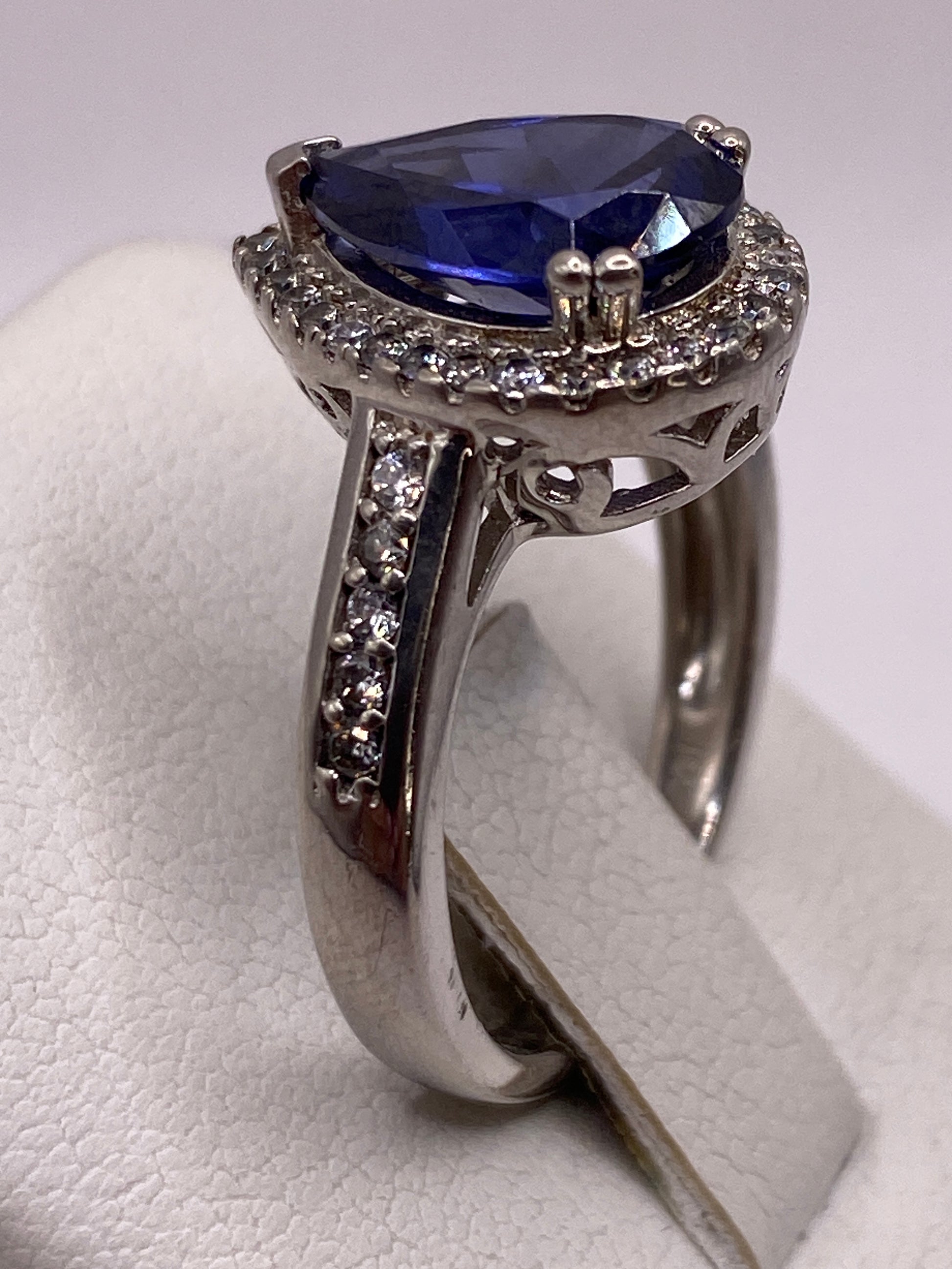 Anillo de circonia azul en mano de mujer con manicure rosa