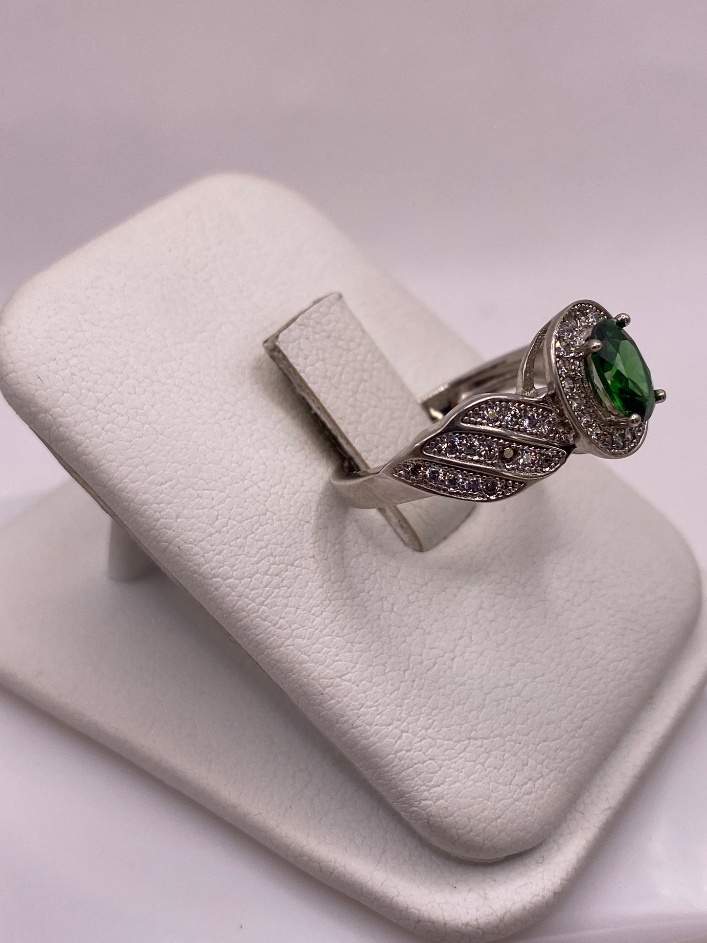 Detalle frontal del anillo solitario verde con alas texturadas en plata