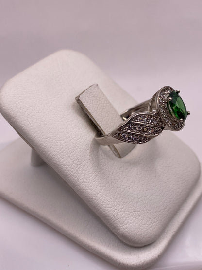 Detalle frontal del anillo solitario verde con alas texturadas en plata