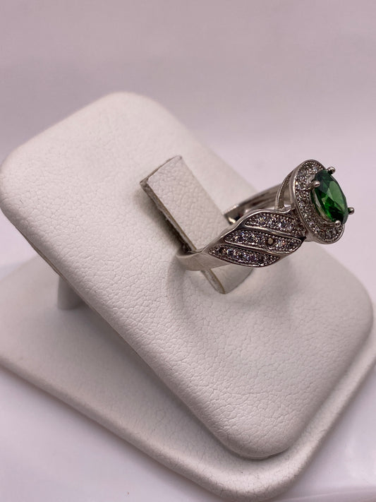 Detalle frontal del anillo solitario verde con alas texturadas en plata