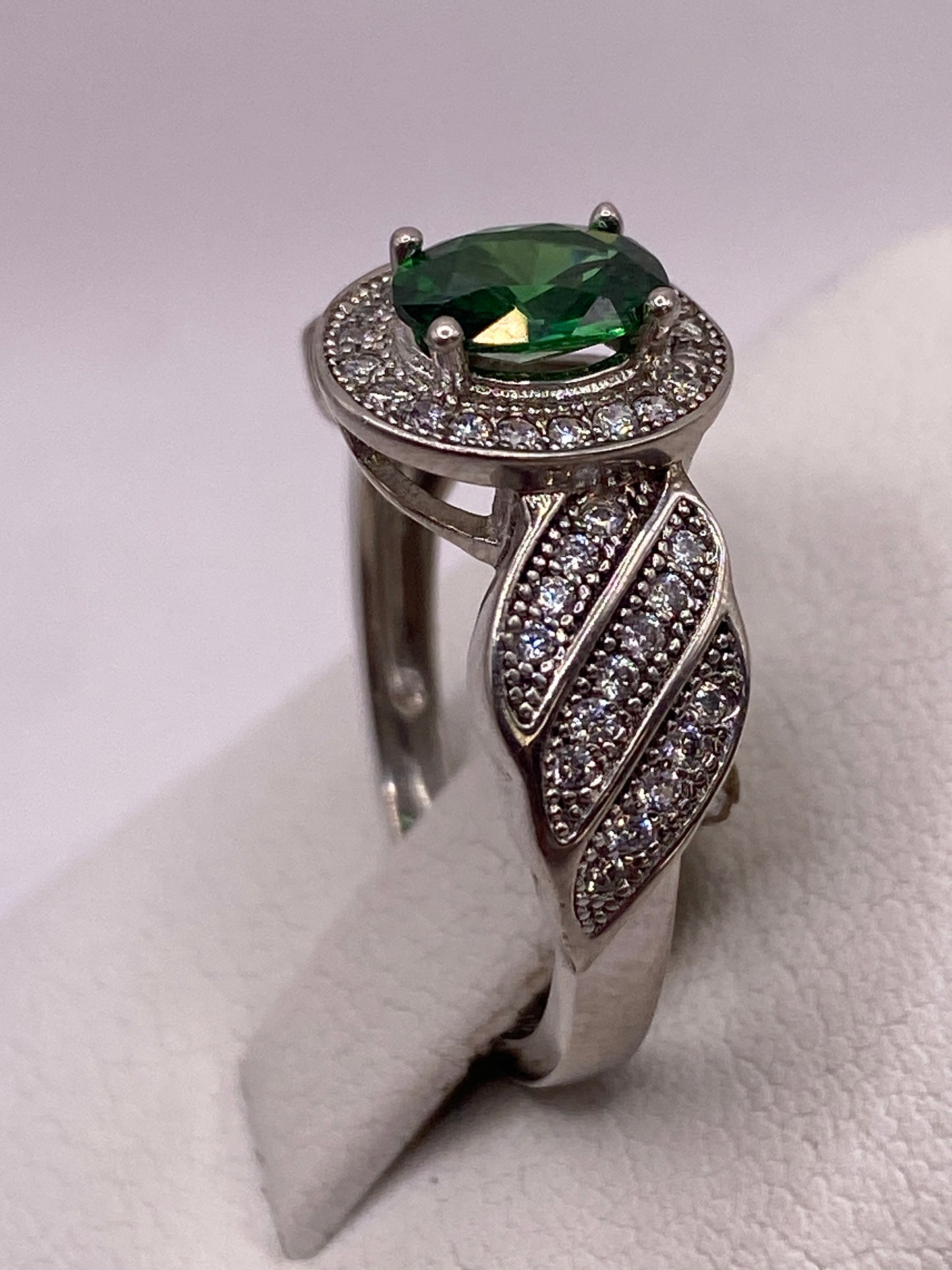 Anillo en dedo mostrando la profundidad del verde y el brillo del halo
