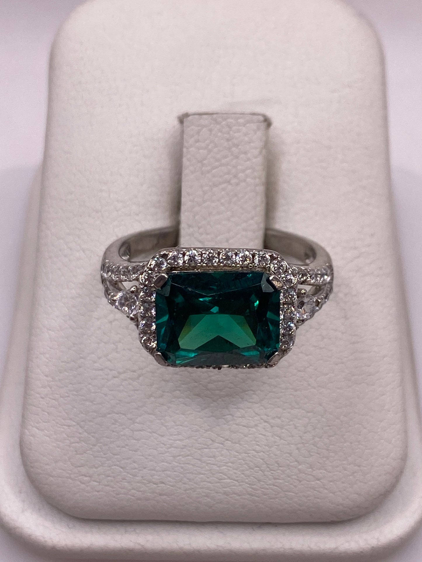 Anillo solitario de plata con circonia verde esmeralda en la mano de una mujer
