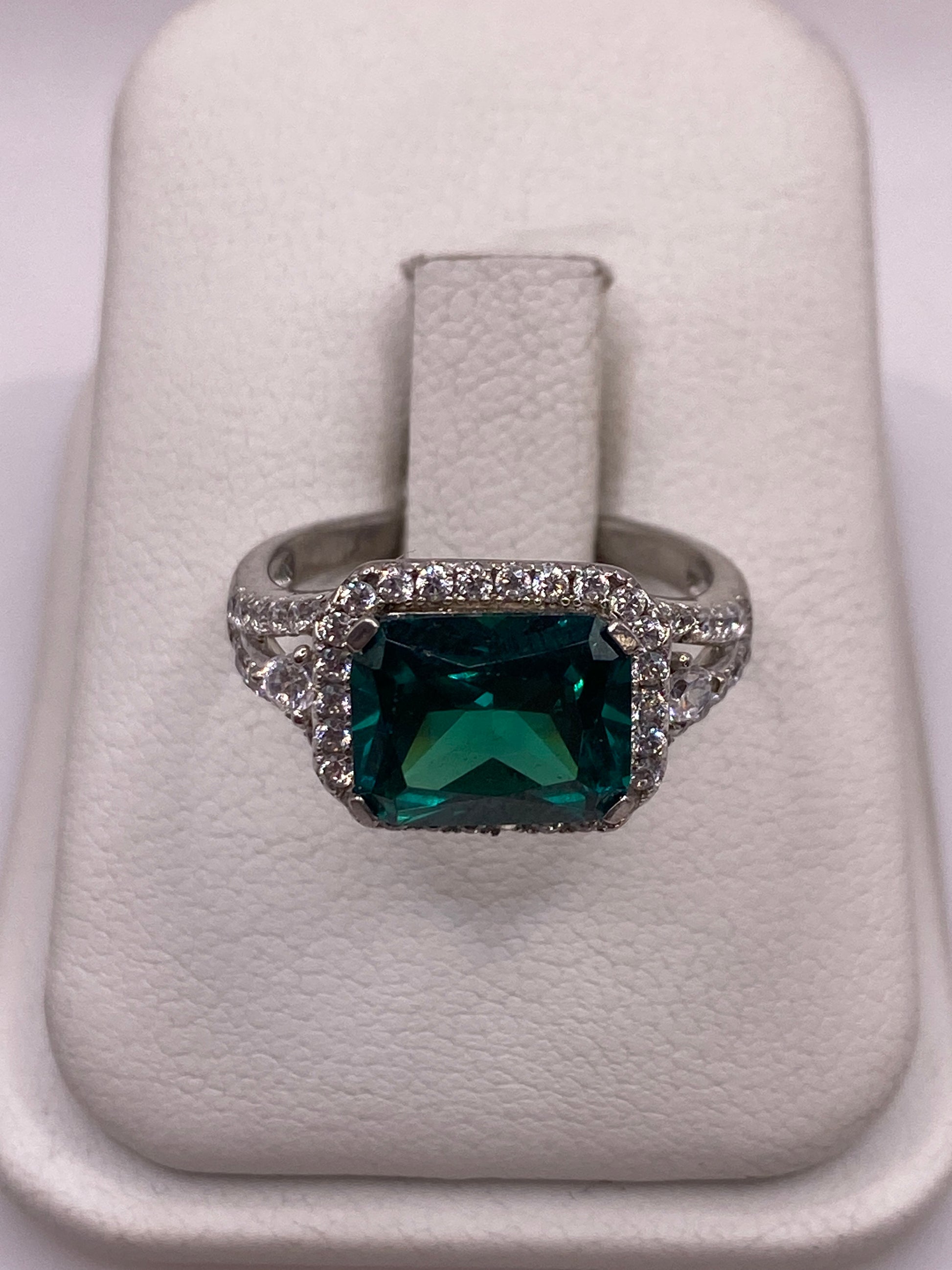 Anillo solitario de plata con circonia verde esmeralda en la mano de una mujer